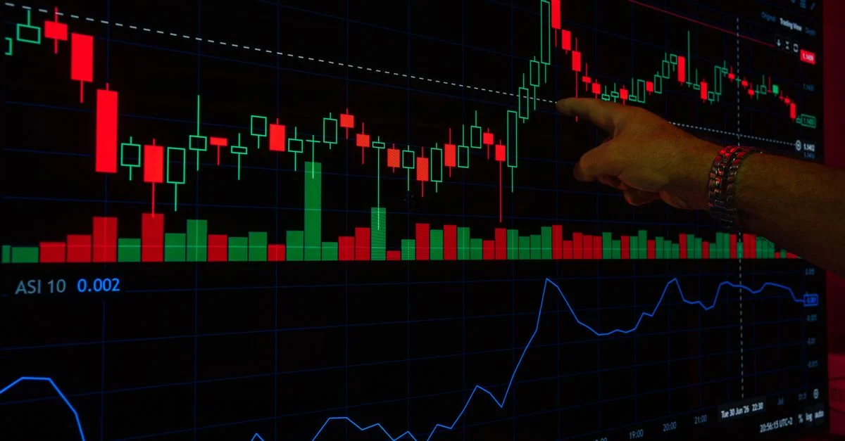 Une main désigne un graphique boursier sur un écran numérique, mettant en évidence les tendances des marchés financiers.