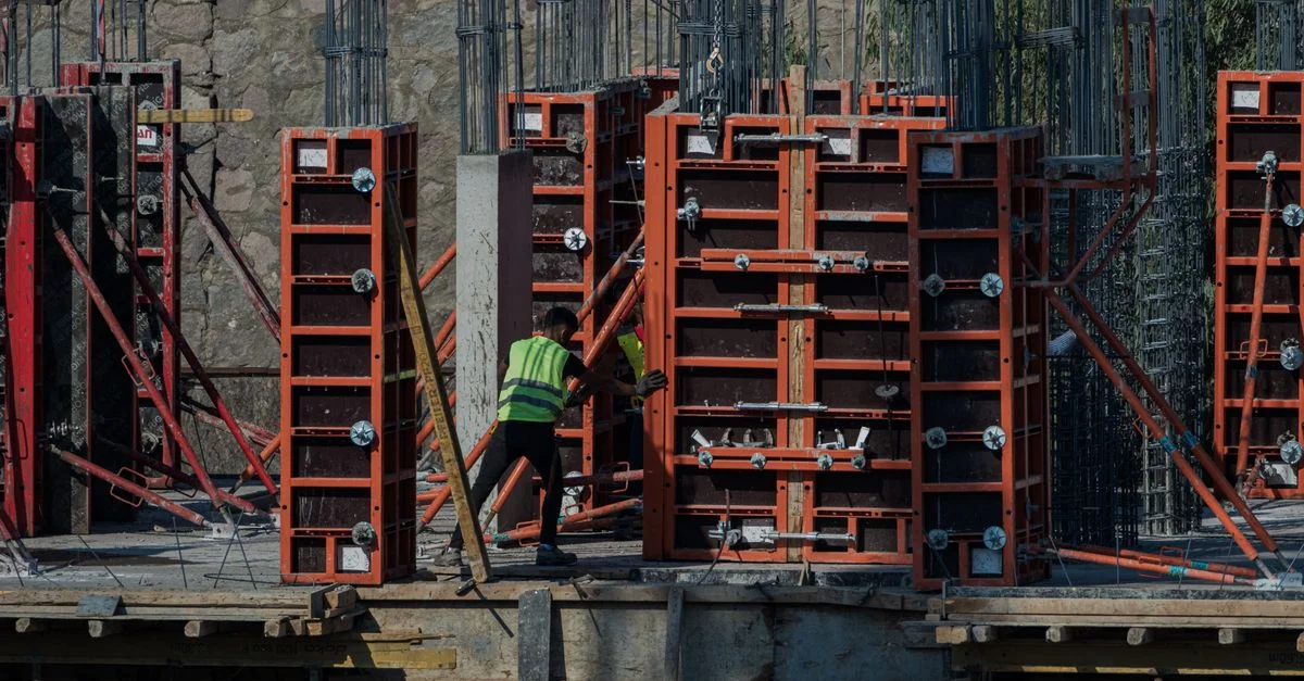 Ouvrier sur un chantier de construction avec une structure rouge à İzmir, en Turquie.