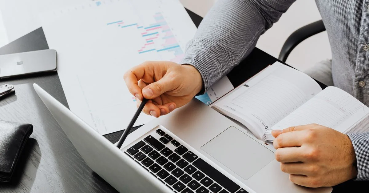 Professionnel utilisant un ordinateur portable et examinant des documents au bureau pour l'analyse des données.