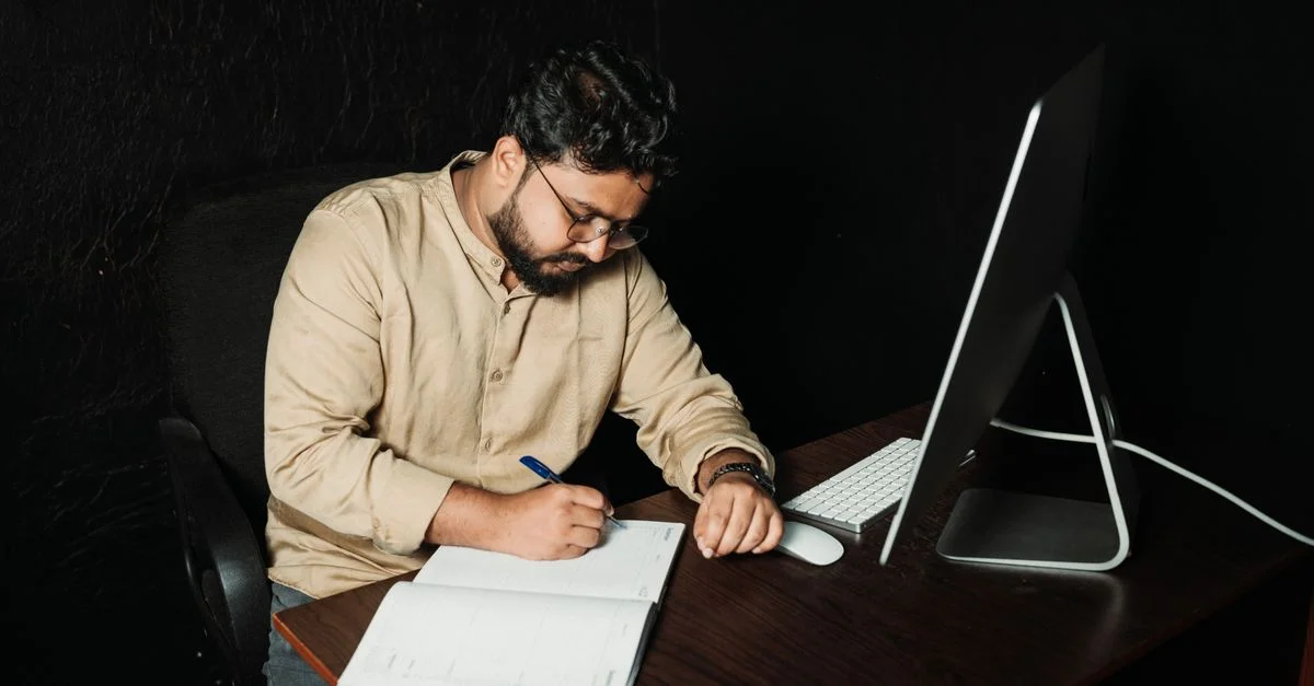 Homme écrivant dans un bureau avec un ordinateur. Travail de nuit axé sur la créativité et la productivité.