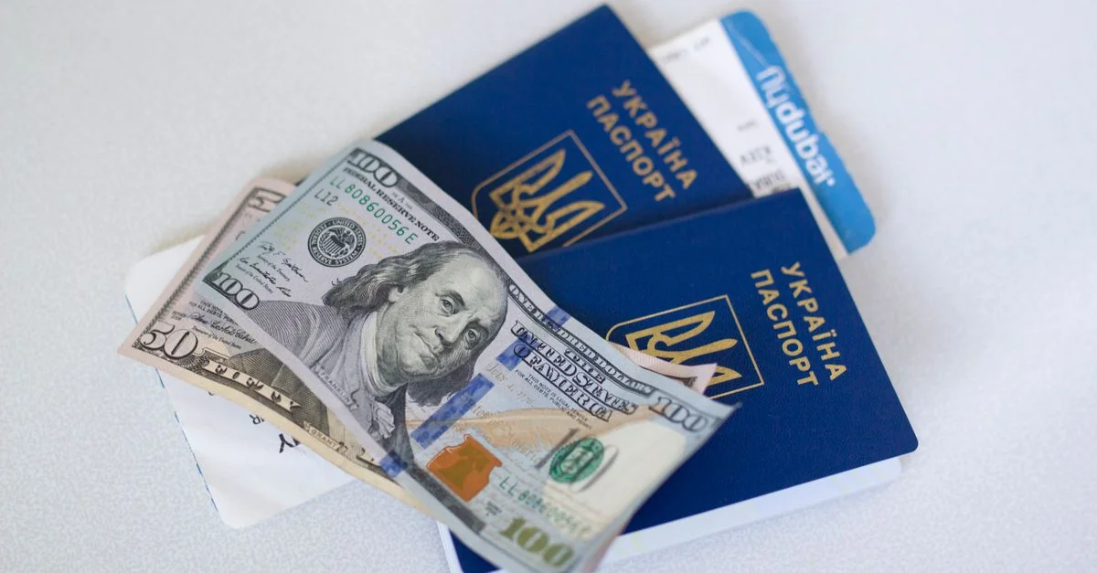 Vue en gros plan de passeports ukrainiens avec des billets en dollars américains, symbolisant la préparation au voyage.