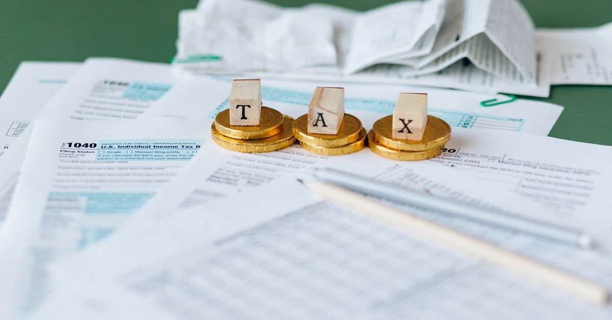Gros plan sur des formulaires fiscaux, des reçus et des pièces de monnaie symbolisant la comptabilité financière et les impôts.
