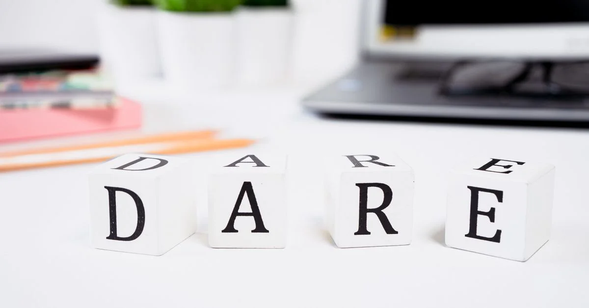 Gros plan de blocs de motivation épelant « DARE » sur un bureau créatif.
