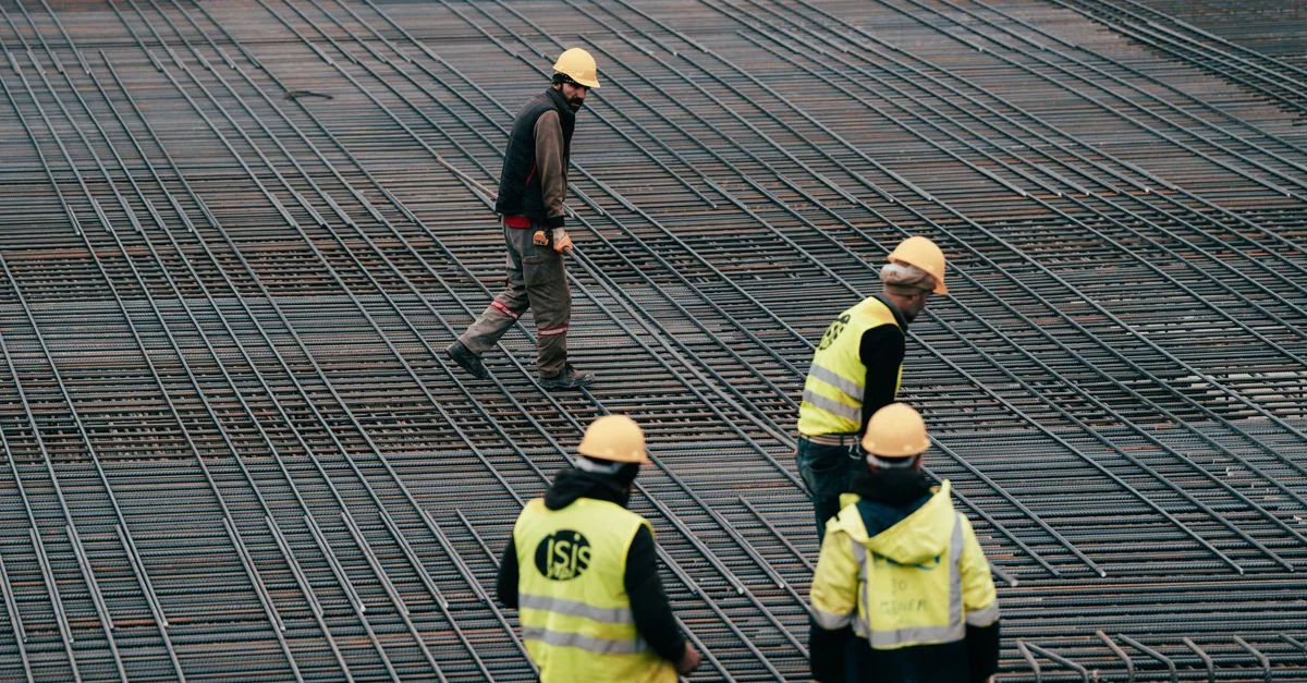 Des ouvriers en tenue de sécurité sur un chantier de construction, en particulier sur les grilles de barres d'armature.