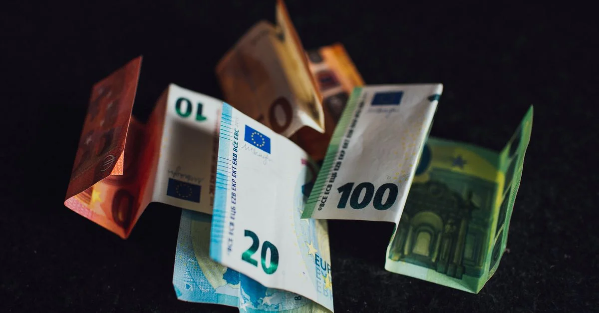 Billets de banque euro variés en coupures de 10, 20 et 100 sur une surface sombre, mettant en valeur la monnaie européenne.