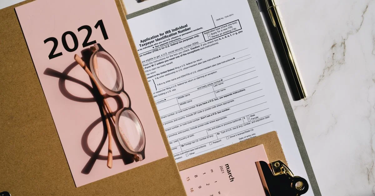 Vue de dessus des formulaires fiscaux, d'un calendrier et de lunettes pour la planification financière de 2021.