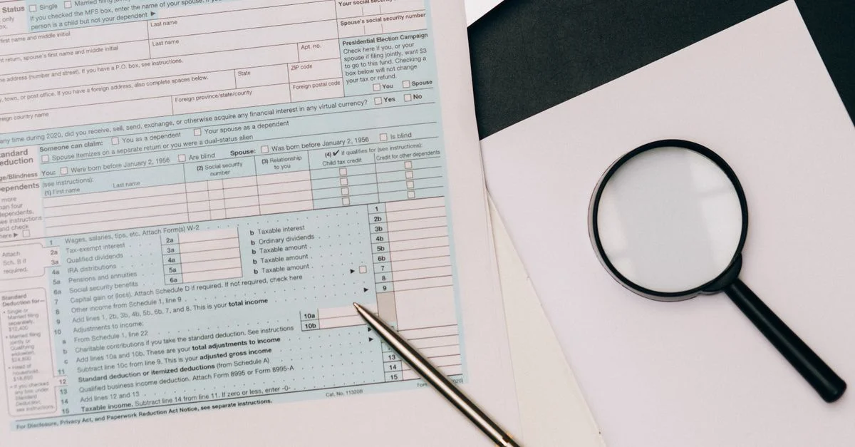 Une vue détaillée d'un formulaire de déclaration d'impôts avec un stylo et une loupe, parfait pour des thèmes financiers.