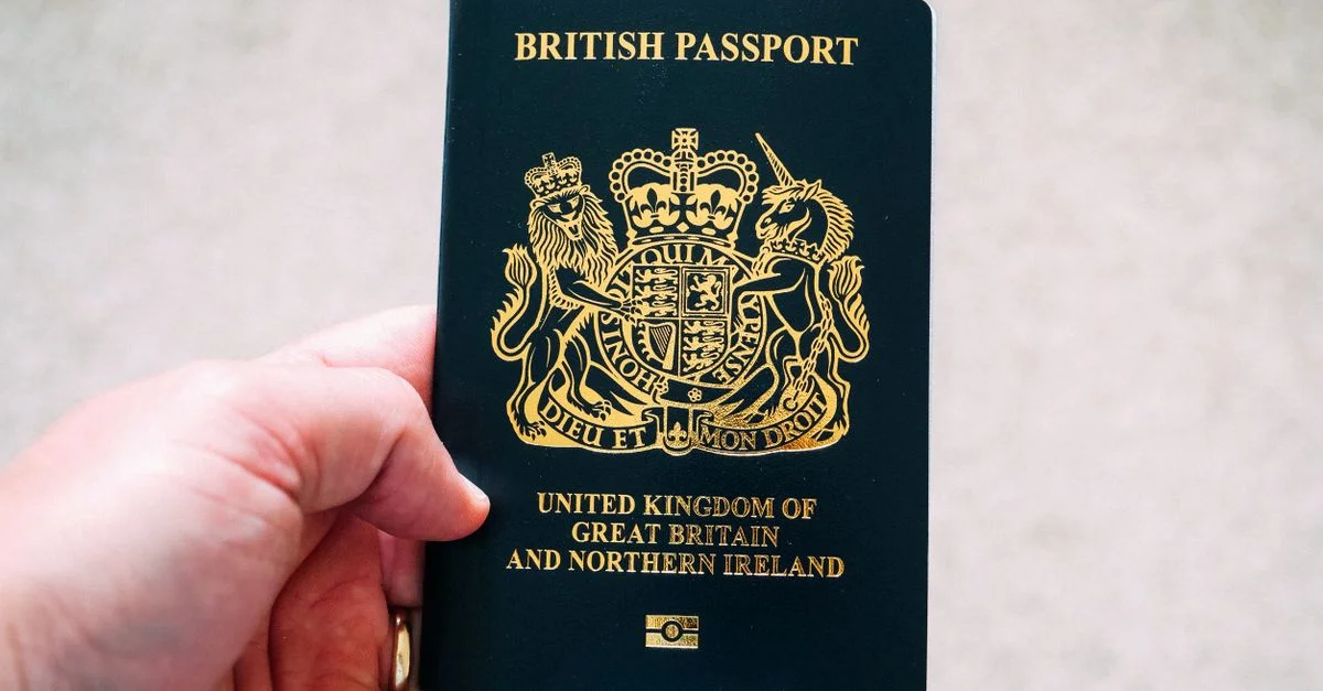 Gros plan sur une main tenant un passeport britannique, symbolisant la citoyenneté et le voyage.