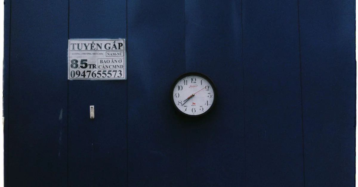 Une horloge murale vintage sur un mur bleu marine avec un panneau en vietnamien.
